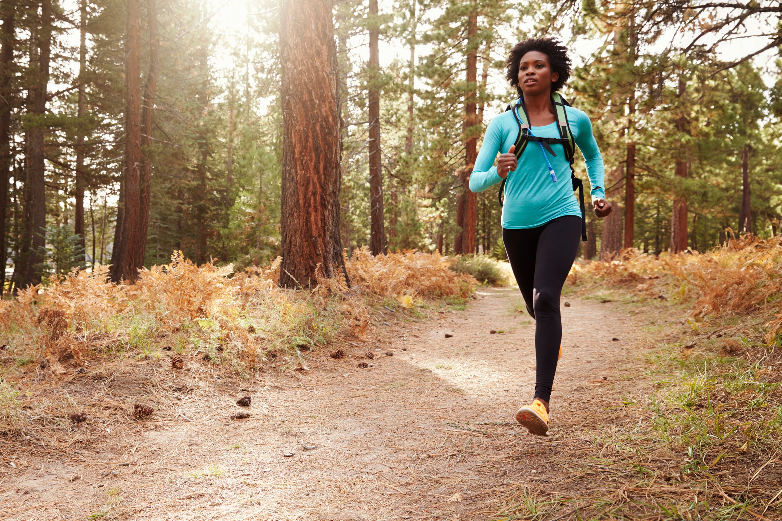 A in athletic clothes runs down a wooded path